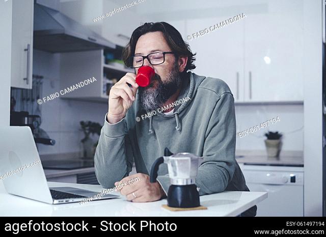 One mature man at home having a coffe in the morning in the kitchen. Single people lifestyle. Modern adult male drinking espresso from traditional italian moka...