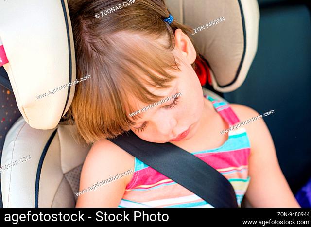 Toddler girl asleep in a child safety seat in a car