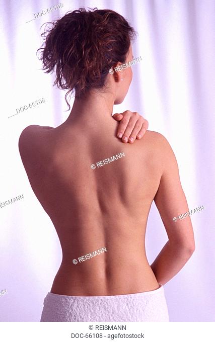 backview - young woman holding her hand on her shoulder