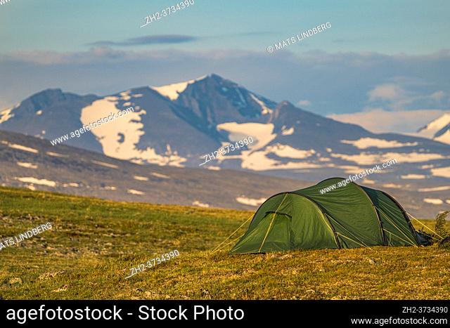 Tent with Sarek nationalpark high mountains in the background, hiking along the Kingstrail in Stora sjöfallet national park in summer time, Swedish Lapland
