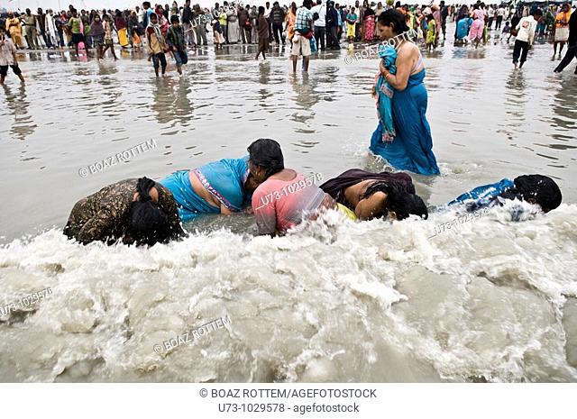 Women dip in the holy water of Gangasagar island during the annual Gangasagar mela