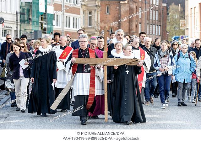 19 April 2019, Schleswig-Holstein, Lübeck: Christoph Giering, Catholic provost, and Petra Kallies, Protestant provost, carry a cross through the old town on an...