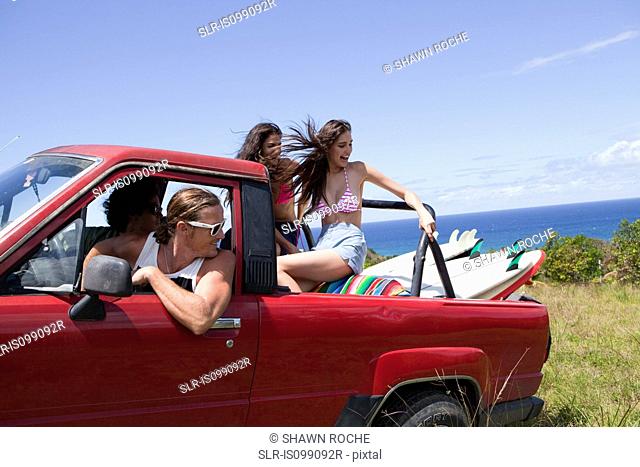 Four young friends driving off road vehicle on vacation