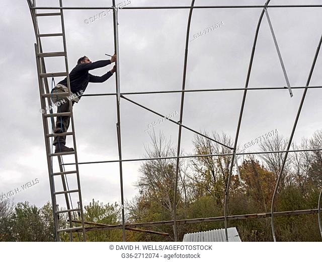 Small-scale farmer builds greenhouses frame on an artisanal organic farm in Johnston, Rhode Island, USA