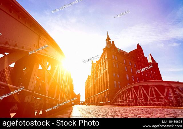 Silhouette of Bridge and Buildings in evening sun rays in low angle view. Speicherstadt Hamburg. Famous landmark of old buildings made with red bricks
