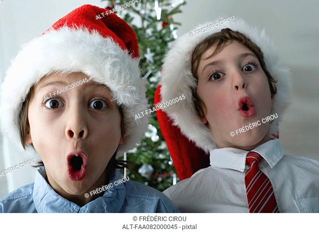 Boys wearing Santa hats, making surprised faces