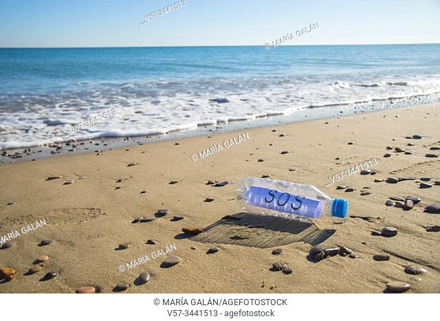 Sea plastic contamination. SOS message in a plastic bottle on the sea shore