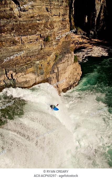 A male kayaker runs leap of faith, a 30 foot waterfall on the Upper Elk River, Fernie, BC