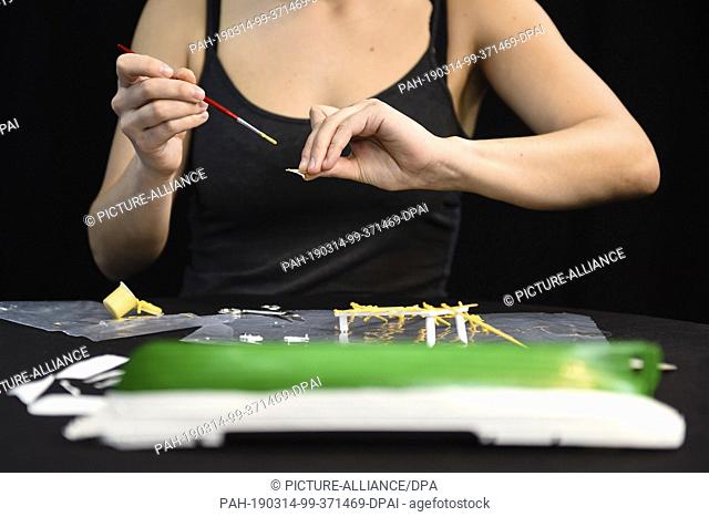 12 March 2019, Berlin: A woman paints a component of a model of the sailing training ship Gorch Fock. (to dpa-Story ""The ""Gorch Fock""-Desaster: Fall in the...