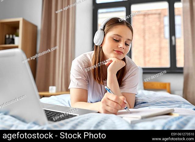 happy student girl in headphones learning at home