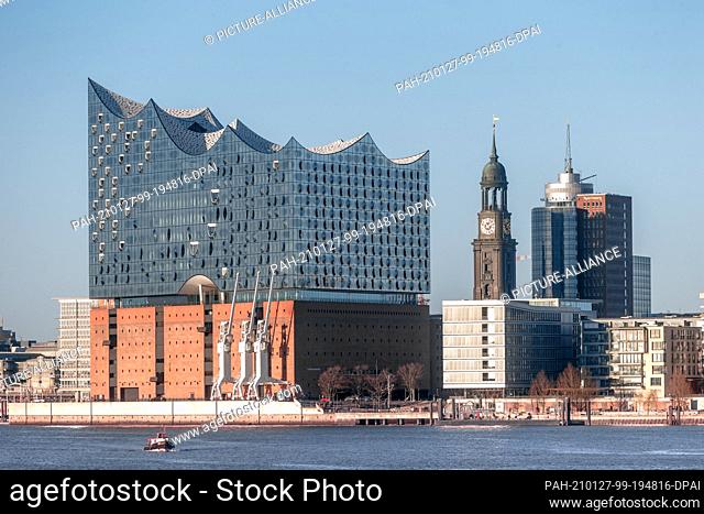 25 December 2020, Hamburg: The building of the Elbphilharmonie (l-r), the tower of the main church St. Michaelis and the Kehrwiederspitze shine in the winter...