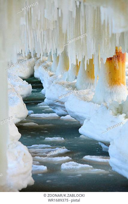 Winter scenery. Baltic Sea. Close up ice formations icicles on pier poles