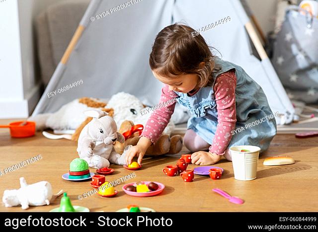 baby girl playing tea party with toys at home