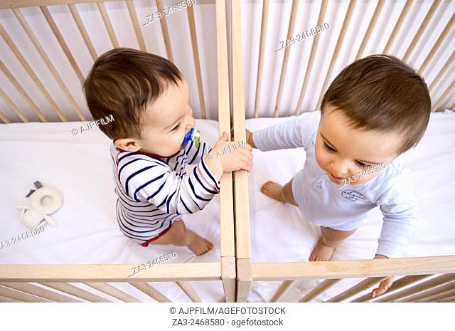 Twin baby boys. 12 month old twin boys playing in their cribs