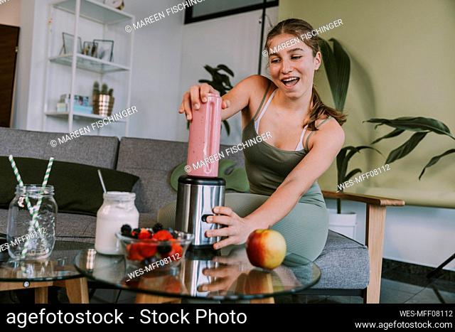 Teenage girl making smoothie while sitting at home