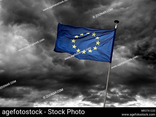 Eine europäische Flagge flattert vor dunklem Wolkenhimmel im Wind