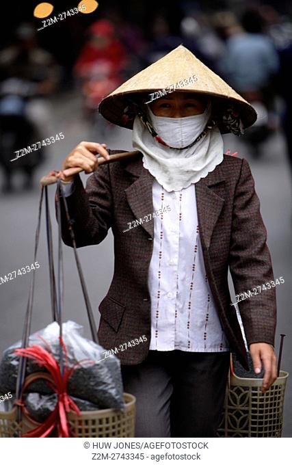 Woman carrying a traditional Vietnamese ‘don ganh’ yoke, Old Quarter, Hanoi, Vietnam