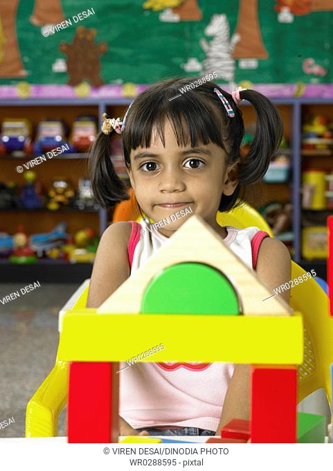 South Asian Indian girl sitting in front of toys in nursery school MR