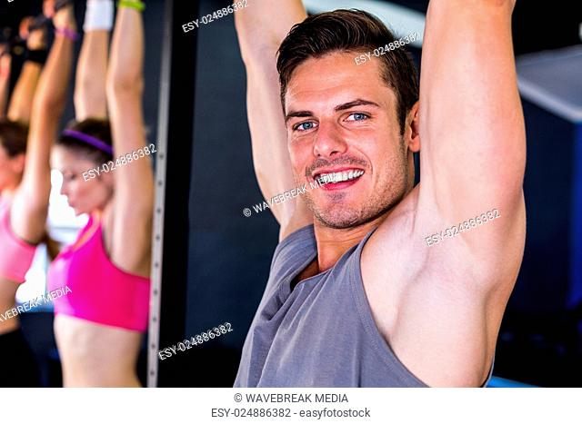 Portrait of smiling man doing chin-ups in gym