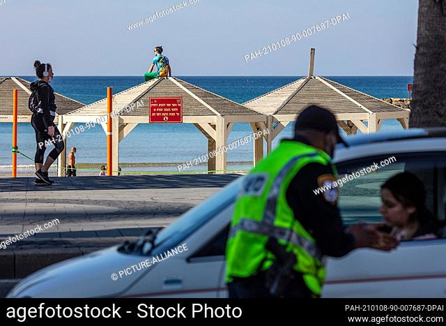 08 January 2021, Israel, Tel Aviv: A man sits on the roof of a pagoda at the beach in Tel Aviv as Israeli police performs checks at a roadblock