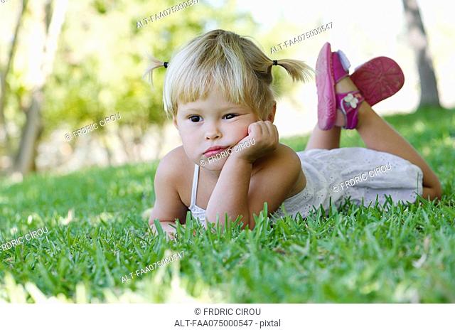 Little girl lying on grass, portrait
