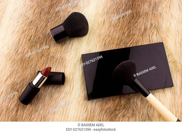Makeup tools on Fur background / featuring eyeshadow palette, lipstick, makeup brushes on a fury background