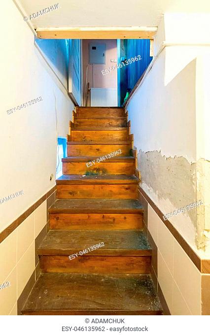 A narrow staircase in the room leading up with wooden stairs