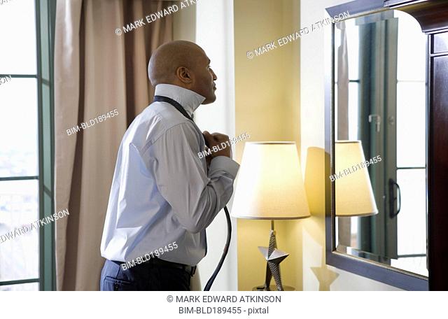 African businessman adjusting tie in mirror