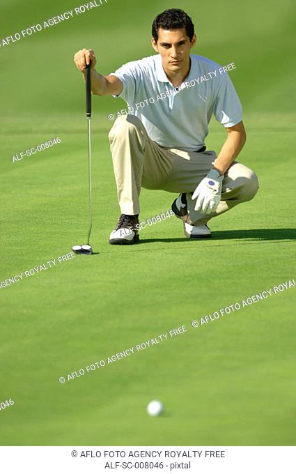 Man lining up a putt on the green