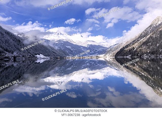 Snow-capped peacks and clouds are reflected in Poschiavo Lake. Lago di Poschiavo, Poschiavo Valley(Val Poschiavo), Graubünden, Switzerland, Europe