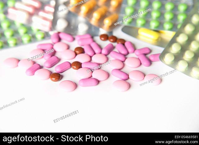 View on scattered pills and tablets in packeges on white background.From above