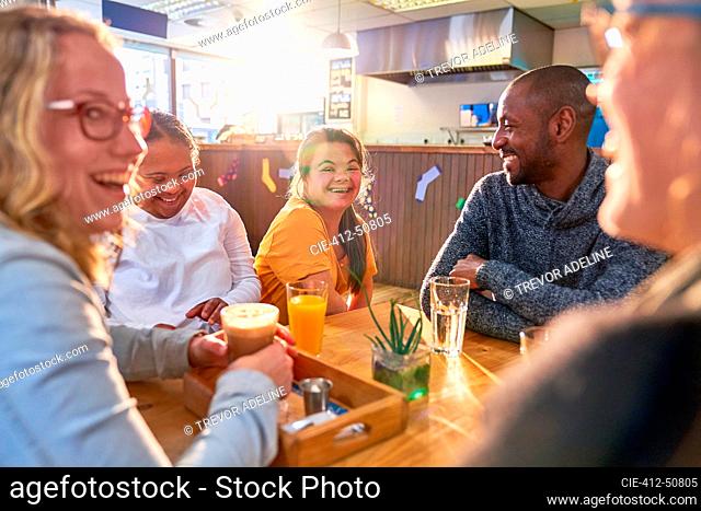 Young women with Down Syndrome laughing with friends in cafe