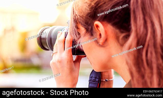 Young beautiful girl is taking a picture with her camera. View from behind