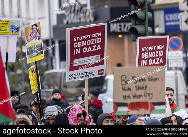 02 December 2023, North Rhine-Westphalia, Duesseldorf: Demonstrators hold up a sign reading ""Stop the genocide in Gaza"" at a pro-Palestine rally under the...