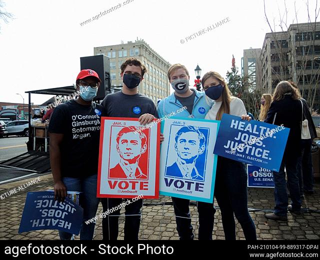 02 January 2021, US, Athens: Joi Siler (l-r), Frederick King, Christopher Summers and Holly Stephens hold campaign posters of the Democratic candidate for a...