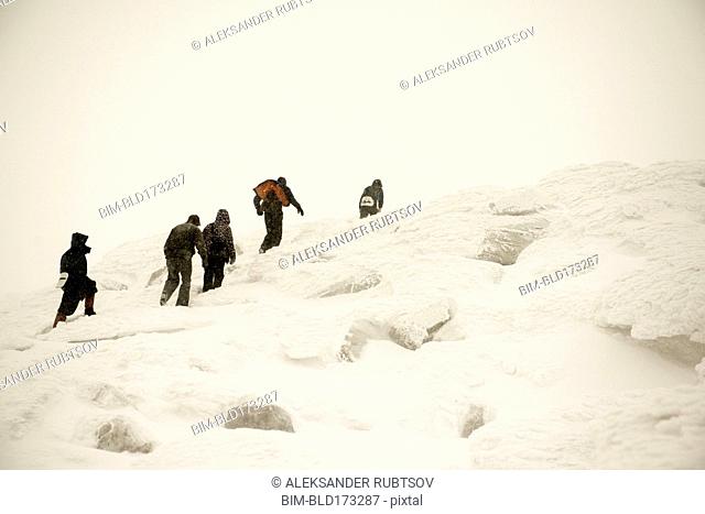 Caucasian hikers climbing snowy mountain