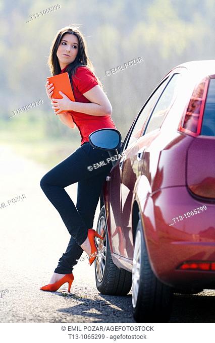 Beautiful student young woman next to a Red car