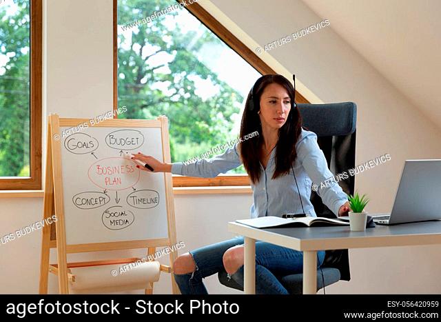 Women on a conference call showing business plan on a childs whiteboard. Working from home concept