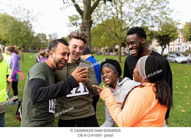 Friend runners with smart phone at charity run in park