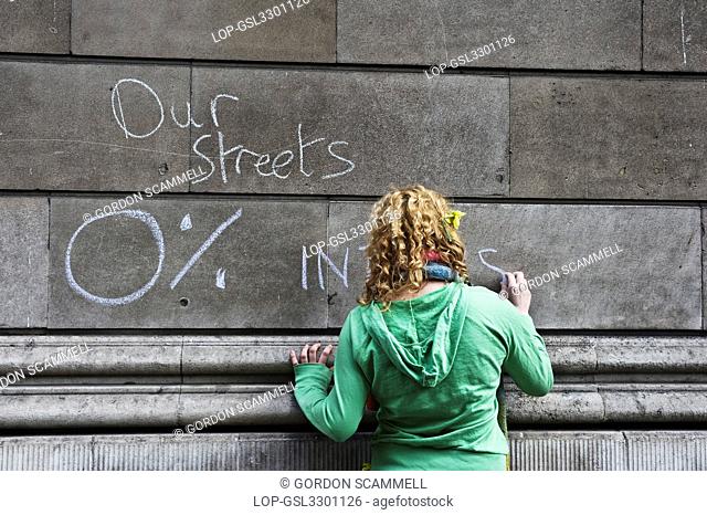England, London, City of London. Protester scrawling graffiti on the wall of the Bank of England at the G20 demonstration in the City of London