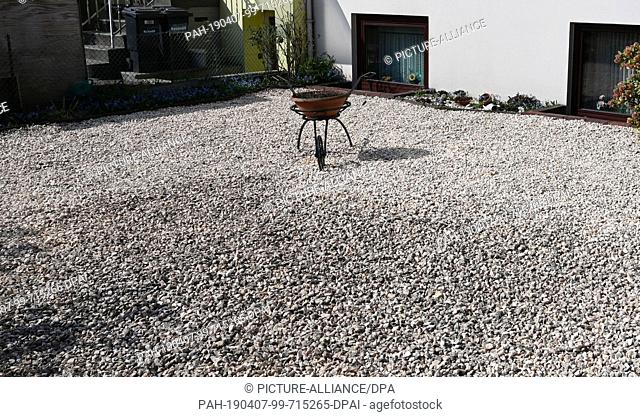 29 March 2019, Bremen: A pot with earth is stuck in a suggested wheelbarrow in a front garden with pebbles. Bremen is now declaring war on the gravel gardens...