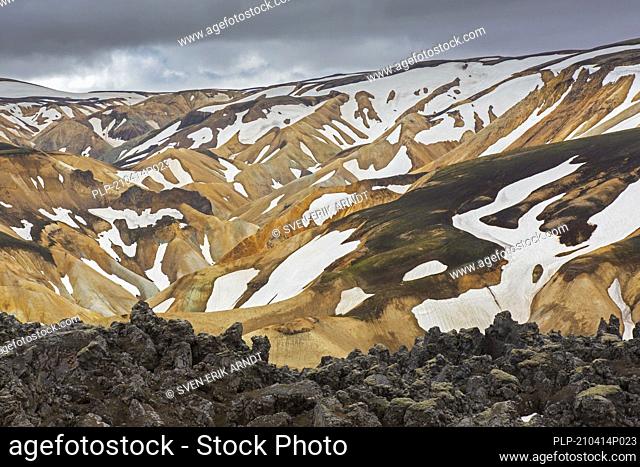 Lava field and sulphur coloured rhyolite mountains at Brennisteinsalda volcano near Landmannalaugar, Fjallabak Nature Reserve, Sudurland, Iceland