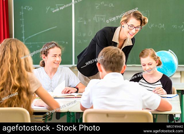 School Students or pupils having group work while geography lesson and the teacher test or educate them in class