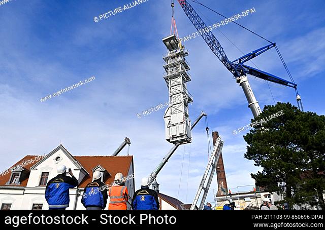 03 November 2021, Saxony, Freiberg: A crane is used to lift the guide frame for the winding tower at the Reiche Zeche research and training mine of the TU...