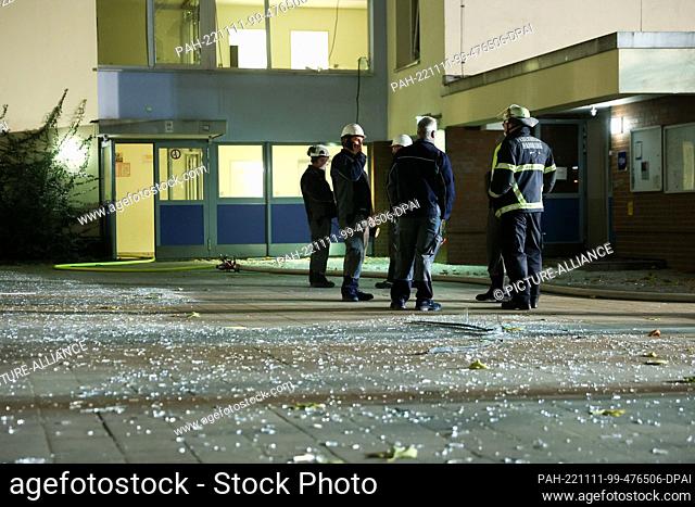 11 November 2022, Hamburg: Emergency personnel confer in front of a house where there has been an explosion. Shards of glass from broken windows lie on the...