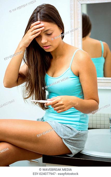 Worried woman looking at pregnancy test