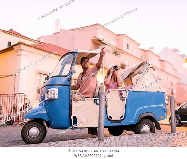 Tuk tuk driver providing tour of the city to a tourist, Lisbon, Portugal
