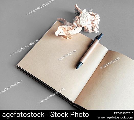 Photo of kraft open sketchbook with blank pages, crumpled paper and pen. Responsive design template. Mockup for placing your design