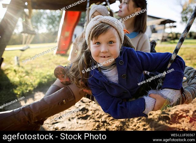 Girl swinging with family on swing at playground