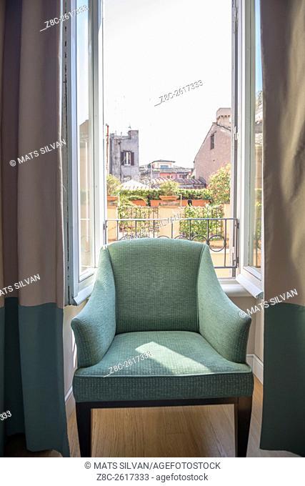 Chair in a window with cityscape behind in Rome, Italy